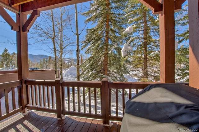 snow covered deck featuring a mountain view and area for grilling