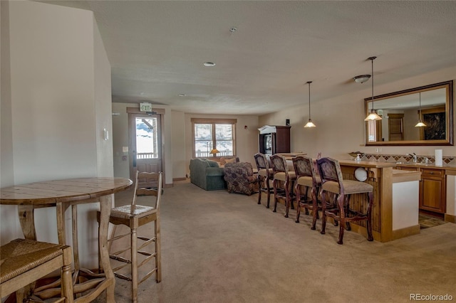 dining room with sink, light colored carpet, and a textured ceiling