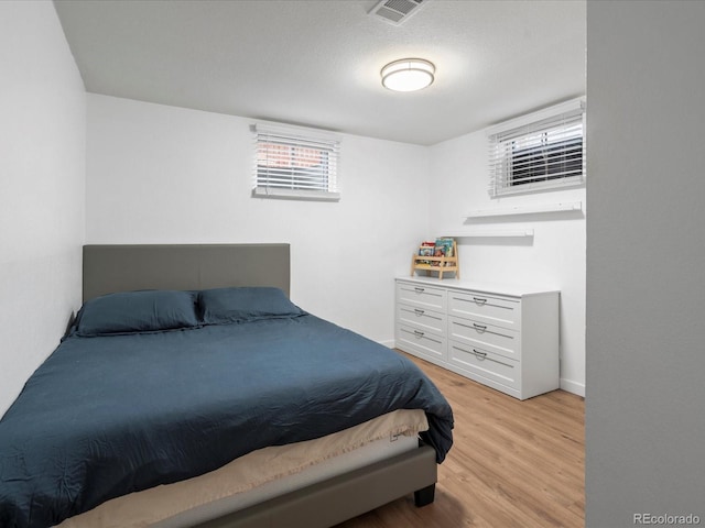 bedroom with a textured ceiling and light hardwood / wood-style floors