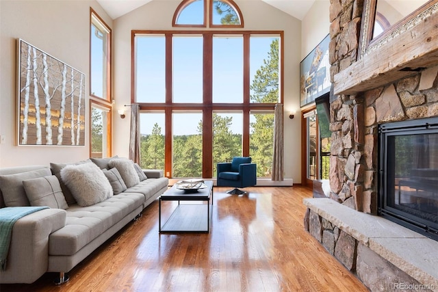 2122 Cramner Ct, Evergreen, CO 80439 - living area featuring high vaulted ceiling, a stone fireplace, wood finished floors, healthy amount of natural light, and baseboards