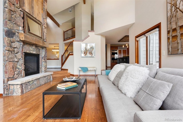 2122 Cramner Ct, Evergreen, CO 80439 - living area with high vaulted ceiling, stairs, a stone fireplace, wood finished floors, and baseboards