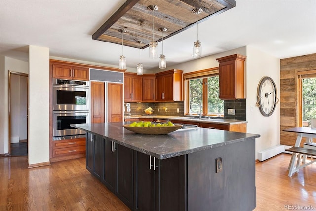 2122 Cramner Ct, Evergreen, CO 80439 - kitchen featuring double oven, a sink, wood finished floors, decorative backsplash, and a center island