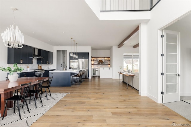 interior space with light wood-style flooring, a chandelier, and beamed ceiling