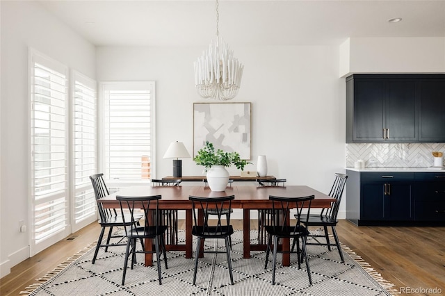 dining area with a chandelier, light wood-type flooring, and baseboards