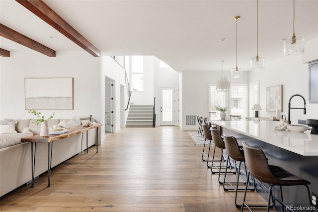 kitchen featuring a breakfast bar, open floor plan, beamed ceiling, light countertops, and light wood-type flooring