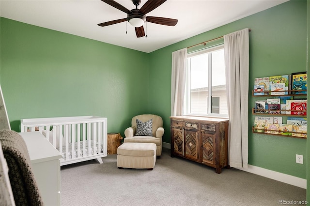 bedroom with a crib, carpet, baseboards, and a ceiling fan