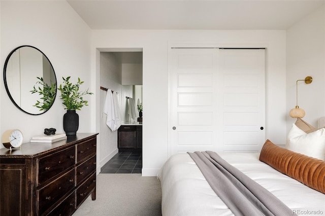 carpeted bedroom featuring a closet, connected bathroom, and baseboards