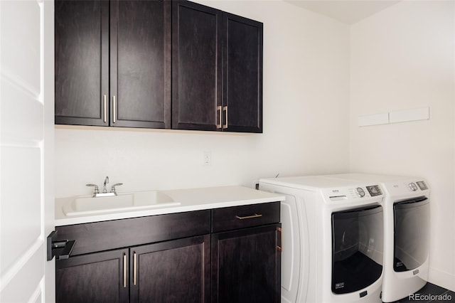 laundry area featuring separate washer and dryer, a sink, and cabinet space