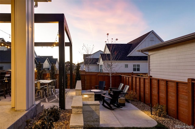 patio terrace at dusk with a fenced backyard and a fire pit