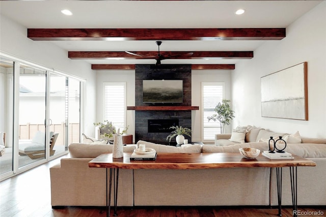 living area with a large fireplace, beam ceiling, wood finished floors, and recessed lighting