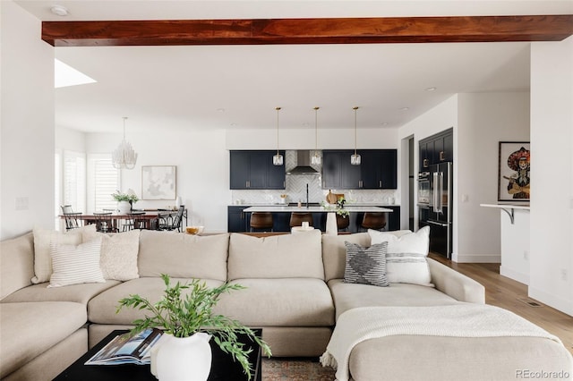 living room featuring light wood-style flooring, baseboards, and beam ceiling