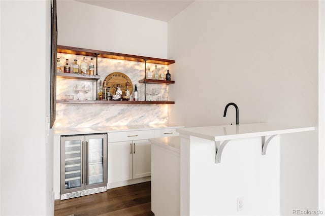 bar with beverage cooler, a bar, and dark wood-style floors