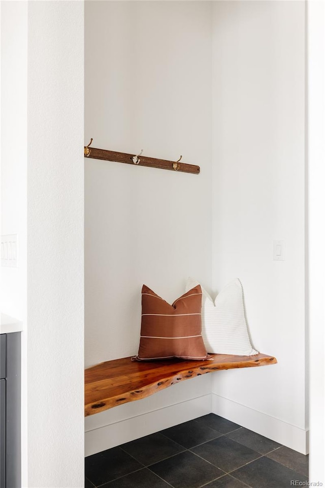 mudroom with dark tile patterned floors and baseboards