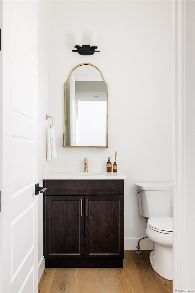 bathroom with baseboards, vanity, toilet, and wood finished floors