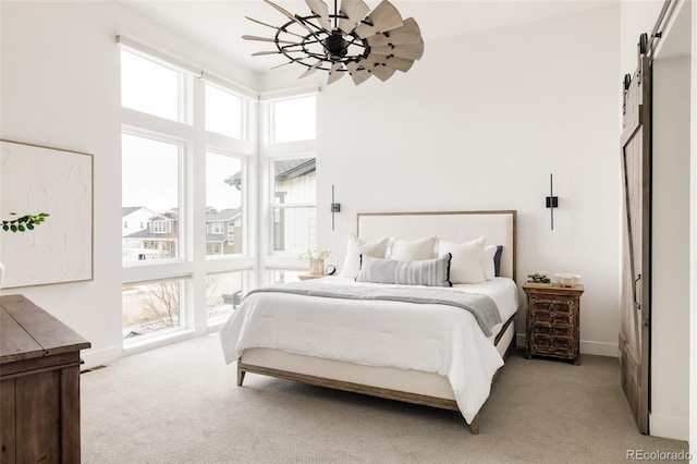 bedroom featuring a barn door, a high ceiling, baseboards, and light colored carpet