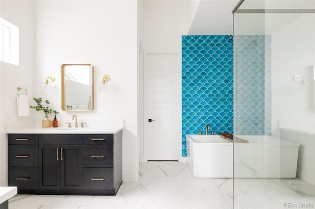 full bathroom featuring marble finish floor, a freestanding bath, and vanity