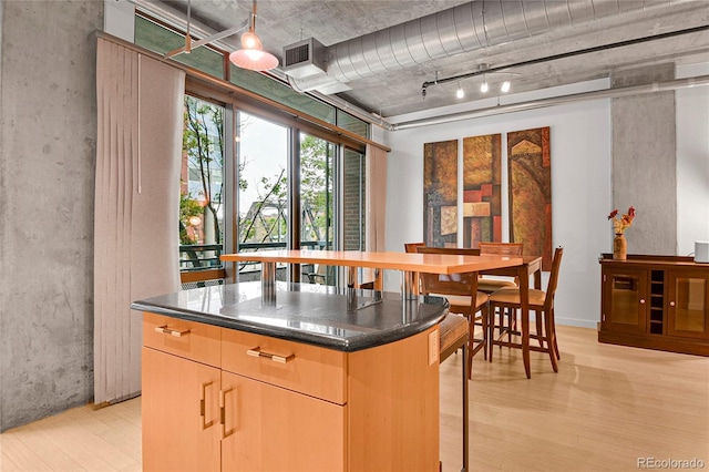 interior space featuring dark countertops, a kitchen breakfast bar, a center island, and light wood-type flooring