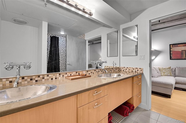 ensuite bathroom featuring double vanity, tile patterned floors, and a sink
