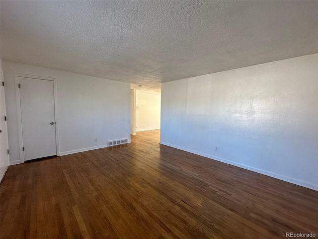 unfurnished room featuring dark hardwood / wood-style flooring and a textured ceiling