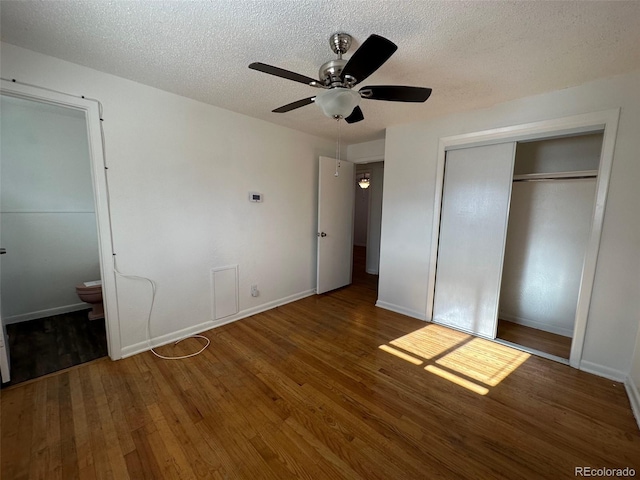 unfurnished bedroom featuring ceiling fan, ensuite bath, a textured ceiling, a closet, and dark hardwood / wood-style floors