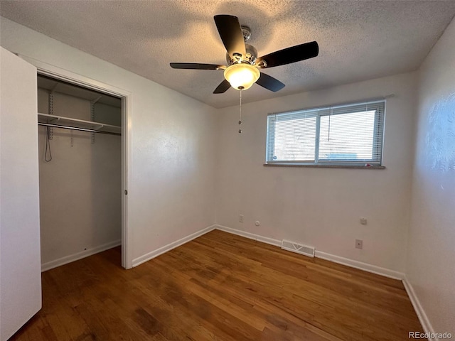 unfurnished bedroom with dark hardwood / wood-style flooring, ceiling fan, a textured ceiling, and a closet