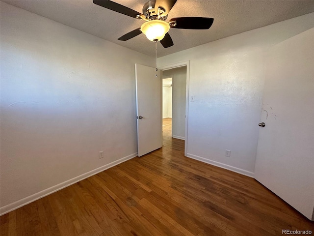 empty room featuring a textured ceiling, ceiling fan, and dark wood-type flooring