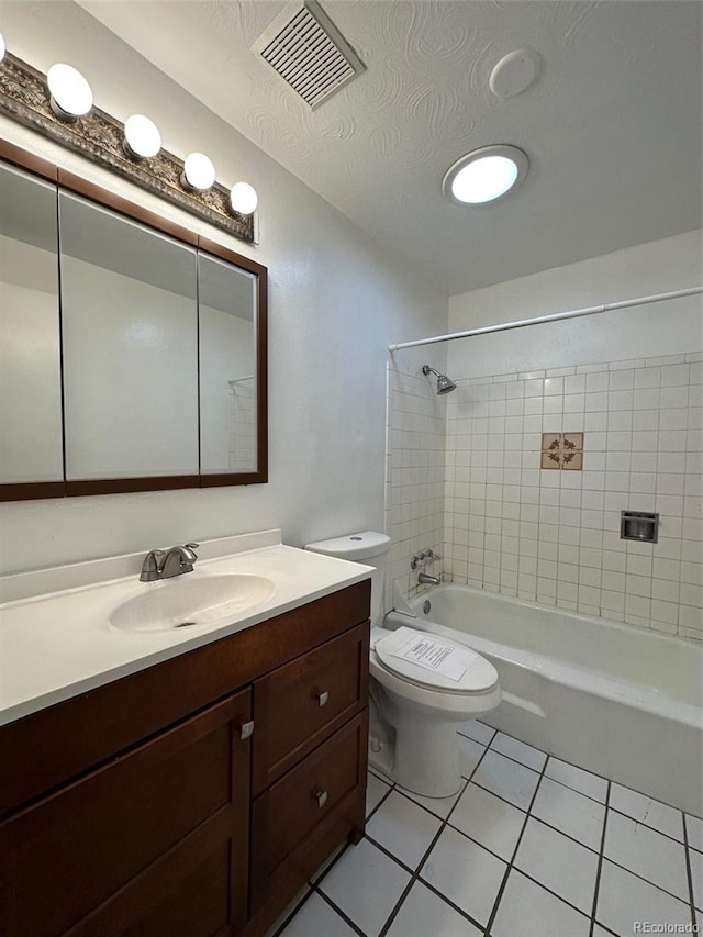 full bathroom featuring tile flooring, tiled shower / bath combo, a textured ceiling, toilet, and vanity