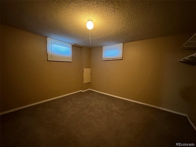 basement featuring dark carpet and a textured ceiling