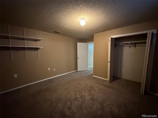 unfurnished bedroom with a closet, dark carpet, and a textured ceiling