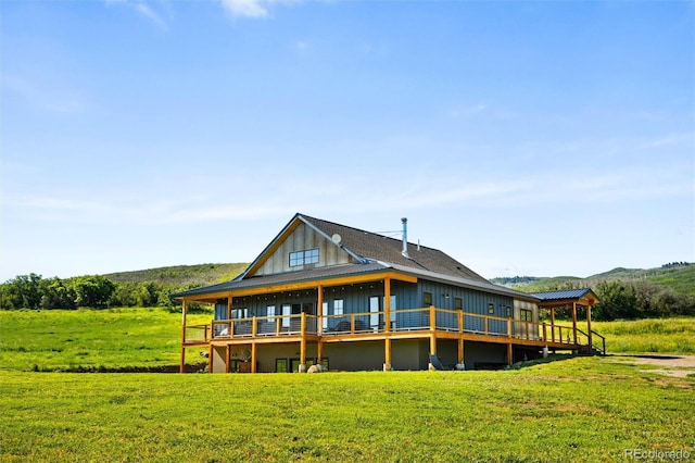 back of property with a wooden deck, a yard, board and batten siding, and metal roof
