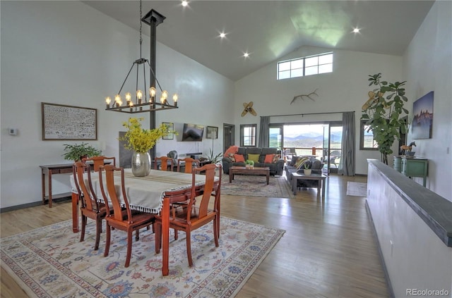 dining room with wood finished floors, high vaulted ceiling, and a chandelier