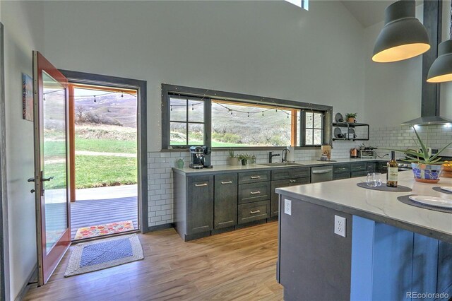kitchen featuring backsplash, light wood-type flooring, stainless steel dishwasher, and a sink