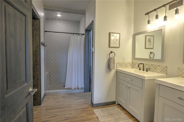 full bath with two vanities, a shower stall, wood finished floors, and a sink