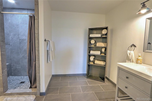 bathroom with baseboards, tile patterned flooring, and a tile shower
