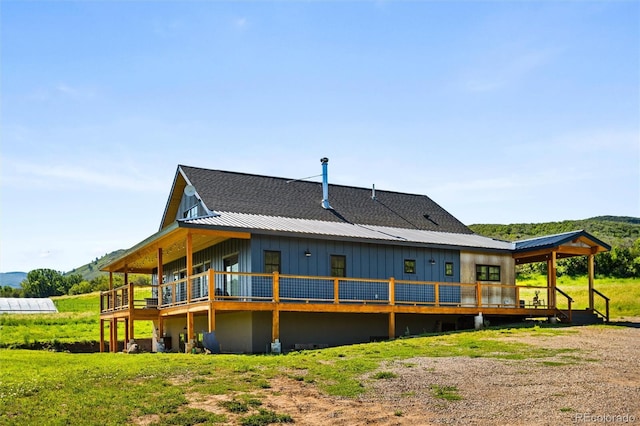 back of house with board and batten siding, a wooden deck, and metal roof