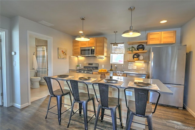kitchen featuring stainless steel appliances, baseboards, decorative backsplash, and dark wood-type flooring