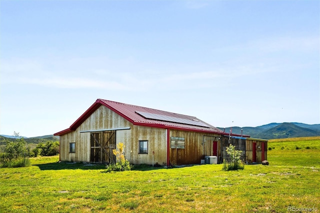 rear view of house featuring an outdoor structure, a yard, a barn, and metal roof