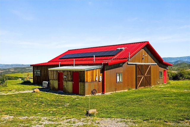 view of barn with a lawn and a mountain view