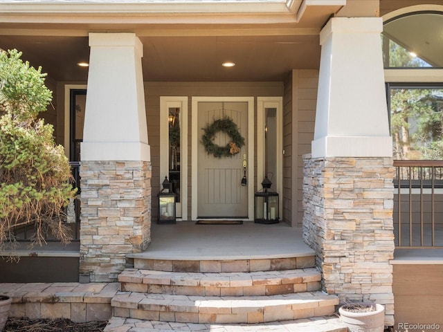 view of exterior entry with covered porch and stone siding