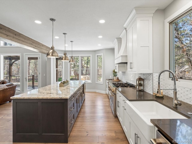 kitchen with stainless steel appliances, a sink, recessed lighting, white cabinets, and plenty of natural light