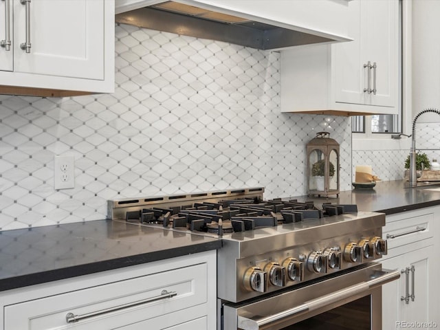 kitchen featuring high end range, tasteful backsplash, custom exhaust hood, and dark countertops