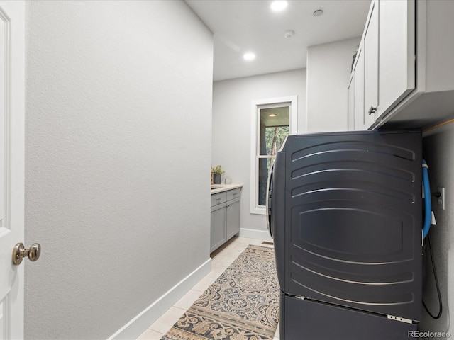 laundry area with light tile patterned floors, cabinet space, baseboards, and recessed lighting