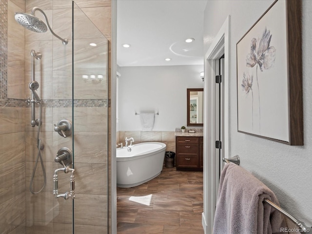 full bathroom featuring a stall shower, a freestanding tub, vanity, and recessed lighting