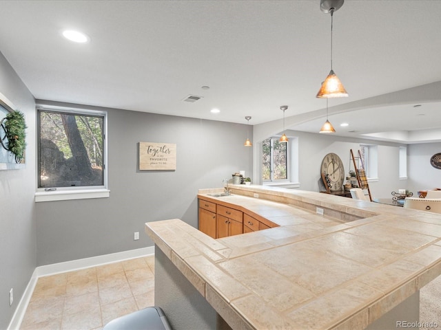 kitchen with recessed lighting, baseboards, healthy amount of natural light, decorative light fixtures, and a sink