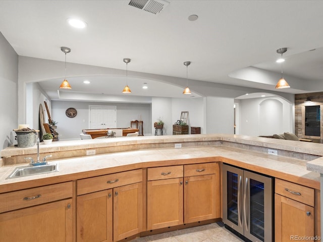 kitchen with wine cooler, a sink, open floor plan, pendant lighting, and recessed lighting