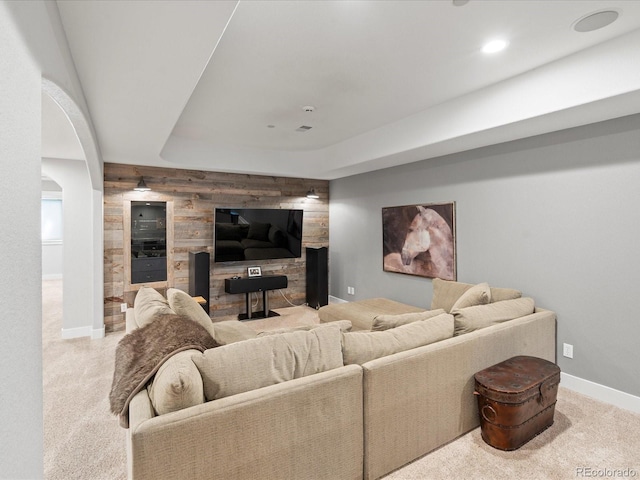 living area with wooden walls, carpet, baseboards, and an accent wall