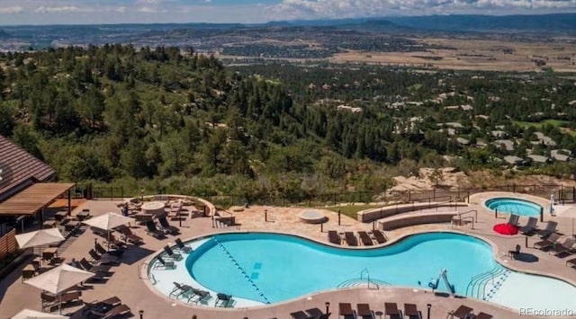 community pool featuring a patio and a wooded view