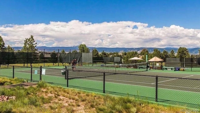 view of tennis court with fence and a mountain view