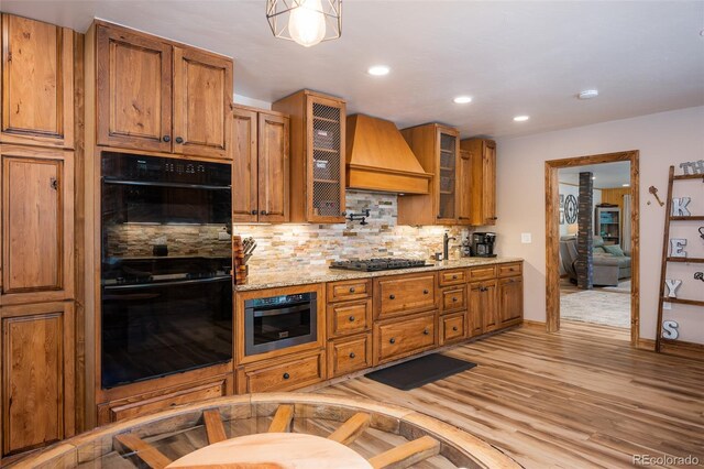 115 Lions Gate Dr, Winter Park, CO 80482 - kitchen featuring custom exhaust hood, tasteful backsplash, dobule oven black, brown cabinetry, and gas stovetop