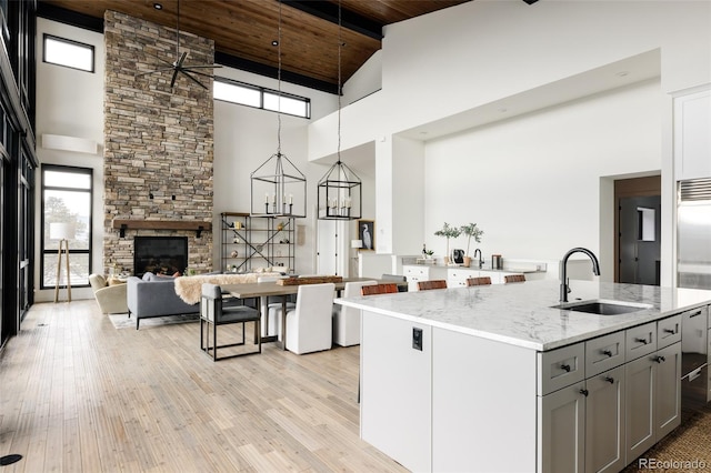 kitchen with light stone countertops, a high ceiling, pendant lighting, wood ceiling, and sink